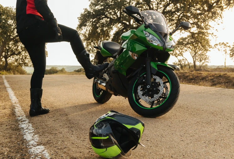 Motard en gilet de haute visibilité près de sa moto immobilisée au bord de la route.
