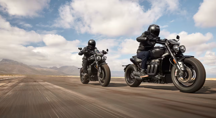 Motard pilotant une Triumph Rocket 3 sur route ouverte lors d'une balade dynamique.