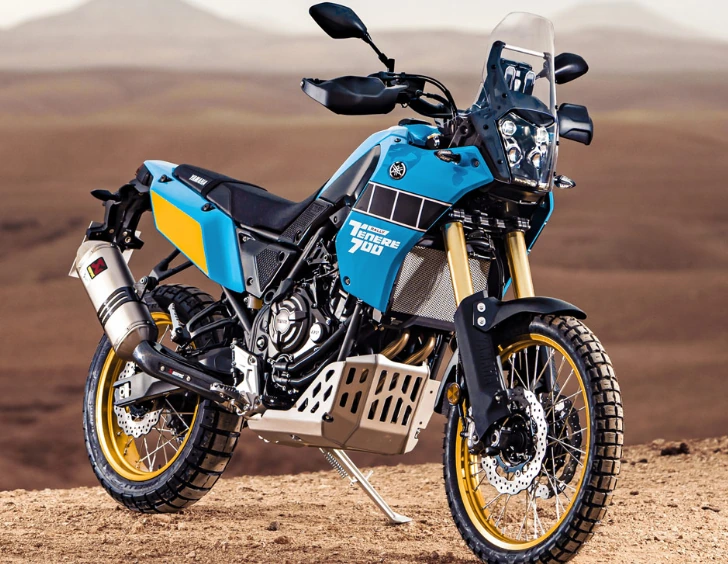 Yamaha Ténéré 700 Rally en livrée bleu-jaune sur terrain cassant, version off-road plus engagée.
